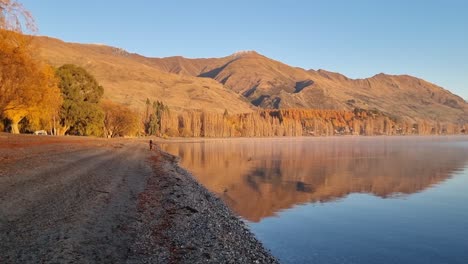 stunning autumn reflection on a calm lake with mountains in the background
