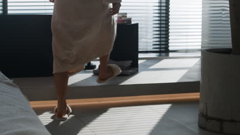 woman in a robe walking in a modern bathroom