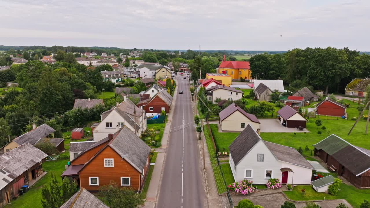 Gade i en lille litauisk by med huse under en blød, skyet aftenhimmel