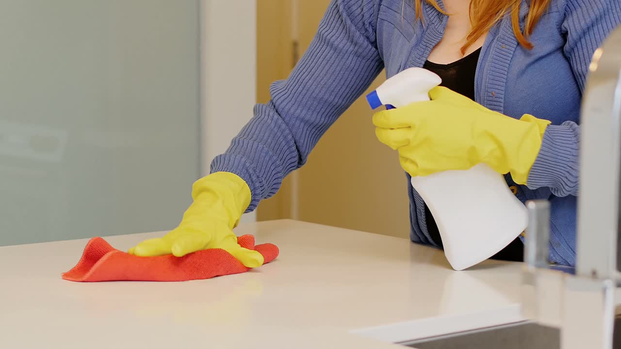 mujer limpiando la encimera de la cocina