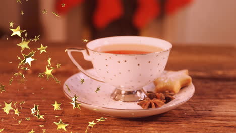 animation of glowing stars falling over cup of tea with christmas cookies