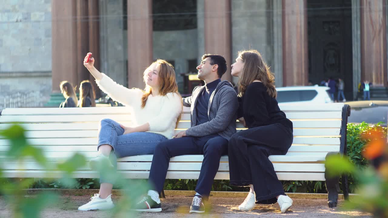 친구 들 이 도시 의 공원 벤치 에서 셀피 를 찍고 있다
