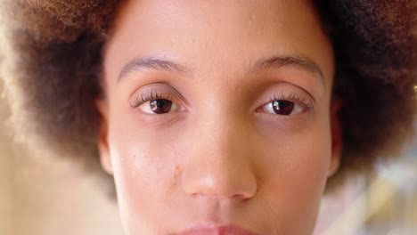 close up portrait of biracial casual businesswoman opening eyes, smiling in office, slow motion