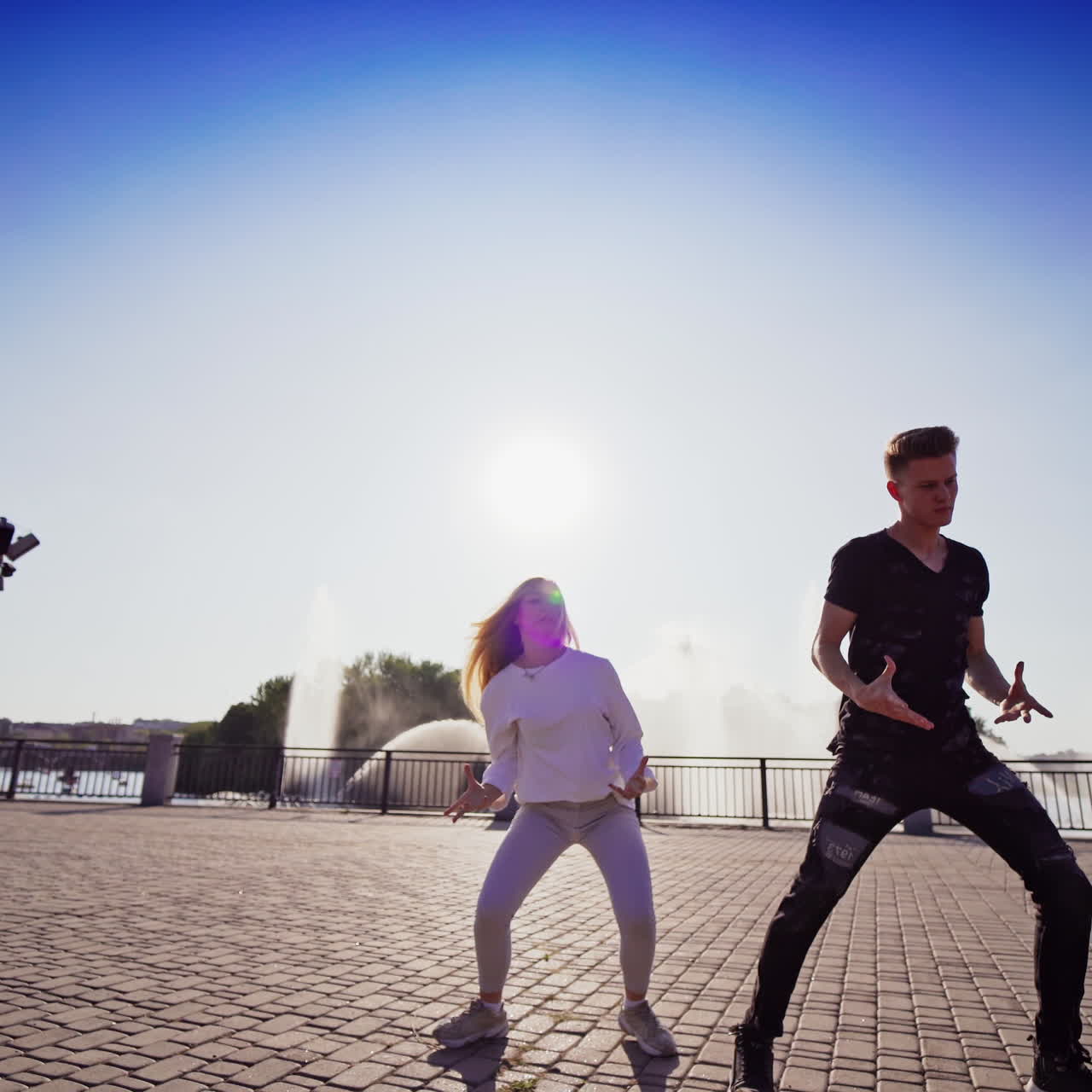 Dancing couple in the city. Outdoor view of young beautiful fashionable couple dancing in the street. Street dance on the sunlight.