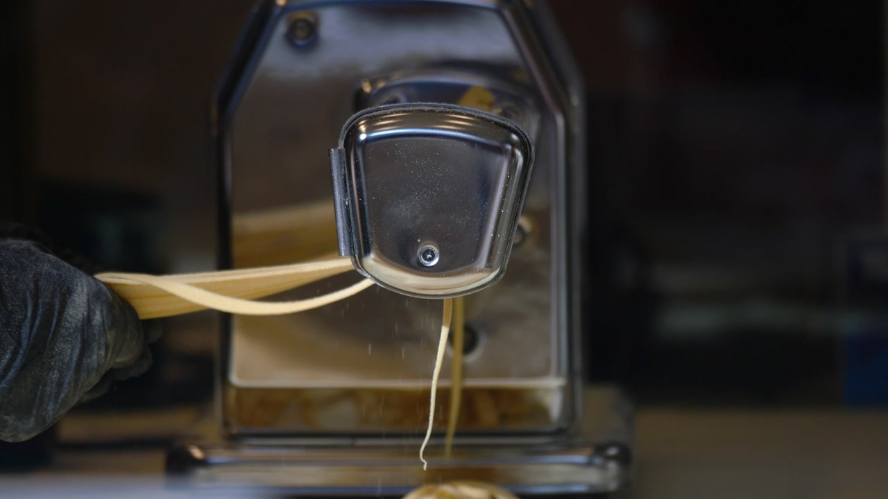 Chef's Hands Making Fresh Pasta with a Machine