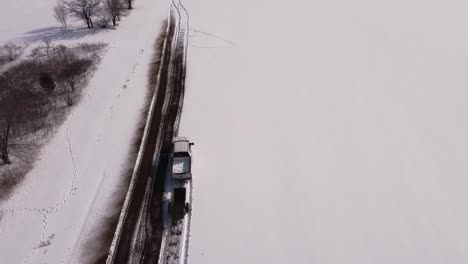 Vastas-Tierras-De-Cultivo-En-Nieve-Profunda-Con-Un-Camión-En-Marcha-Tirando-De-Un-Esparcidor-De-Estiércol-En-El-Sureste-De-Michigan