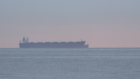 buque de carga en la distancia del océano tranquilo al atardecer - ancho