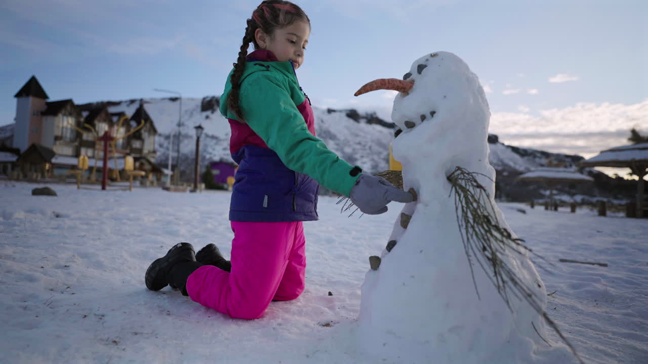 Girl girl building snowman in snowy mountains