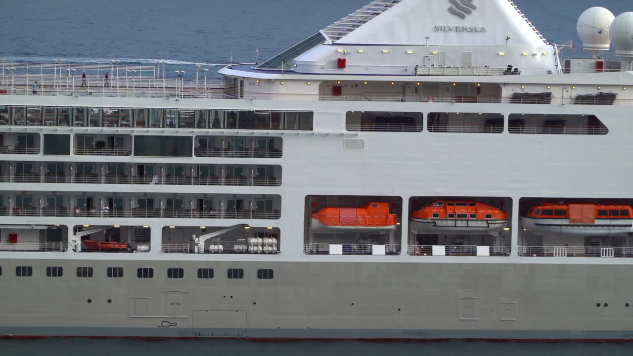 La Condamine, Monaco - 4 juli 2025: Sidovy av ett stort kryssningsfartyg som ligger i hamn i Monaco, med flera däck, balkonger och passagerare som njuter av havsutsikten