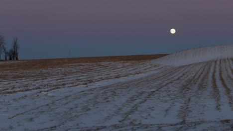 a super moon overtop of a snow covered field