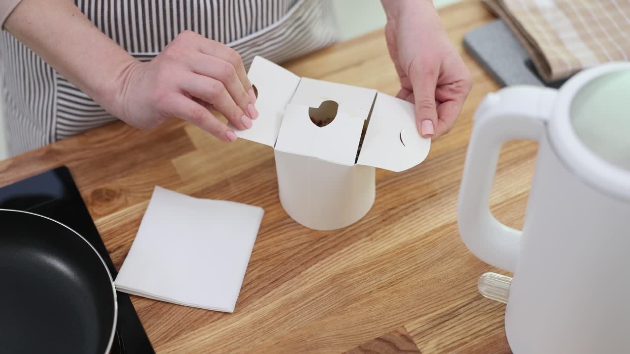 Woman opening a food container on a kitchen counter