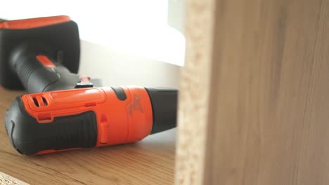 orange power drill on a wooden shelf