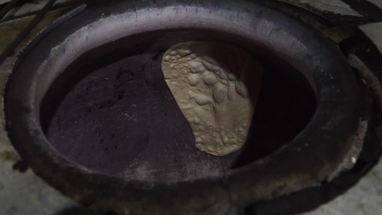Chef preparing naan bread in traditional Indian restaurant on charcoal stove