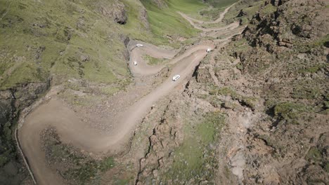 Aerial-view-as-vehicles-descend-steep-dirt-switchbacks-of-mountain-pass