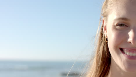 young caucasian woman smiles brightly at the beach, with copy space