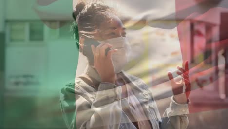 Italien-Schwenkt-Flagge-Gegen-Asiatische-Frau-Mit-Gesichtsmaske,-Die-Auf-Der-Straße-Mit-Dem-Smartphone-Spricht