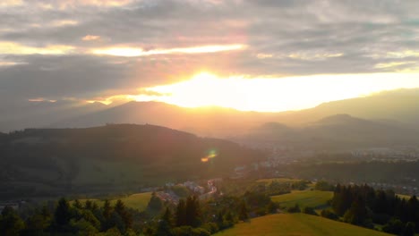 aerial revealing cute little mountain town during gorgeous golden sunset filling the beautiful landscape