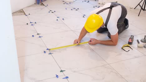 a craftsman in overalls installs tiles on the floor repairs inside the house construction