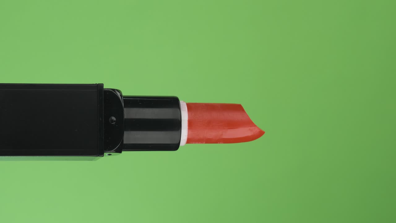 rotación horizontal de un lápiz labial rojo abierto, en una pantalla verde. primer plano.
