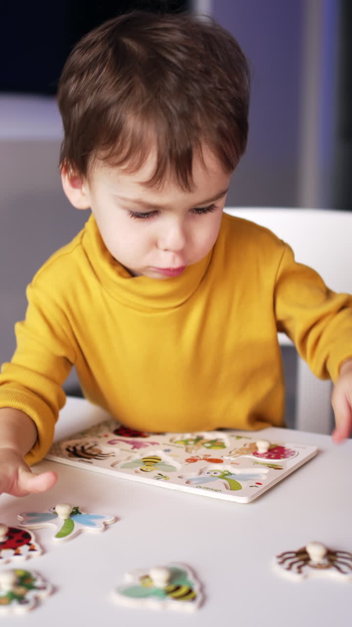 Bellissimo bambino caucasico che gioca con i puzzle alla scrivania