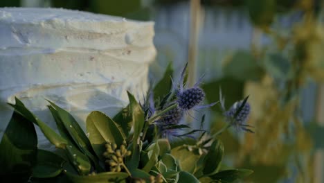 Pastel-De-Bodas-Blanco-Cubierto-De-Hojas-Verdes-En-Una-Recepción-De-Bodas-De-Verano-Al-Aire-Libre