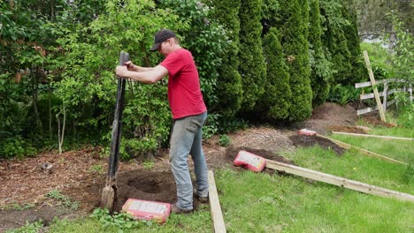 man use post hold digger to clear out a hole for a fence post