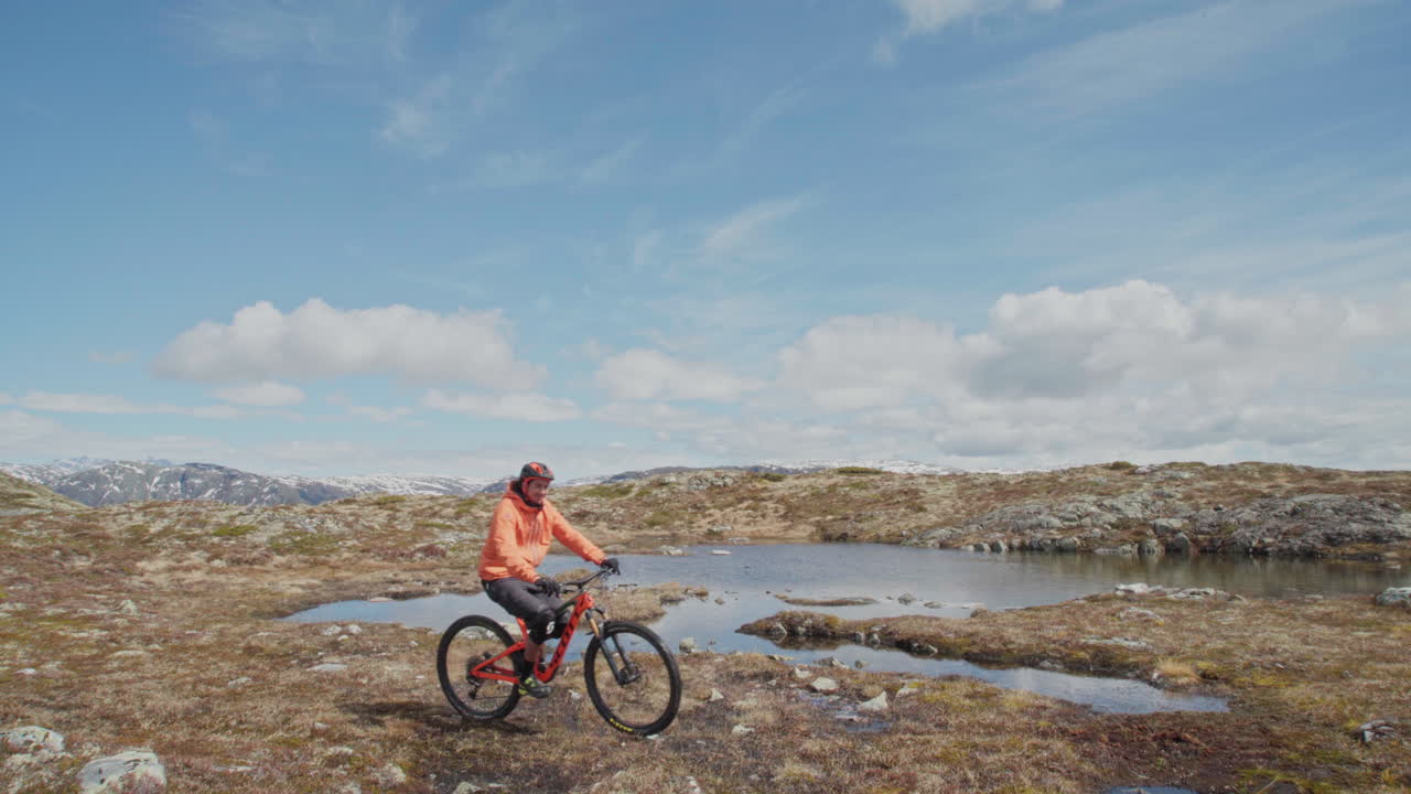 Epic mountain biking adventure above the fjords near Sogndal, Norway. Rider tackles rugged trails surrounded by dramatic cliffs, lush green hills, and stunning Nordic scenery