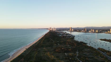 coastal nature parklands dividing a boat harbor and coastline with an urban city skyline rising above in the foreground