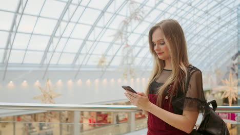 Las-Niñas-Usan-El-Teléfono-Móvil,-Desenfocan-La-Imagen-Del-Interior-Del-Centro-Comercial-Como-Fondo.