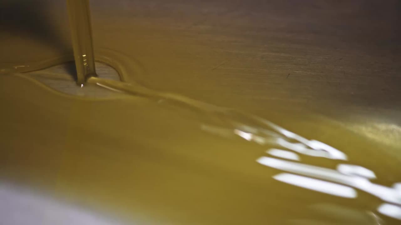Olio d'oliva dorato che scorre fluidamente dalla macchina durante la lavorazione in Portogallo.