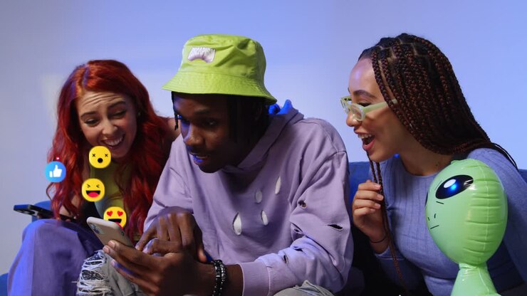 Group Of Gen Z Friends Looking At Mobile Phones With Motion Graphics Emojis Showing Multiple Social Media Notifications Liking And Reacting To Online Content 3