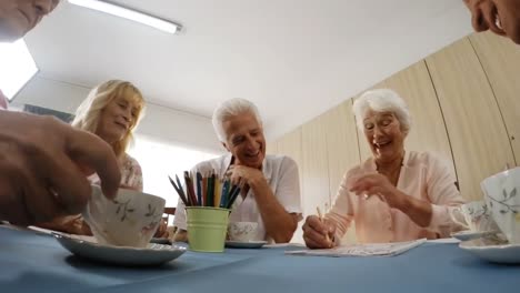 hombre y mujer mayores pintando mientras beben café