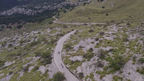 Tracking-shot-of-group-cyclists-riding-at-Coll-dels-Reis-mallorca-Spain,-aerial