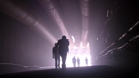 silhouette of many construction workers walking out from a large tunnel