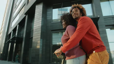 Happy-African-American-Couple-Riding-E-Scooter-Together-in-City