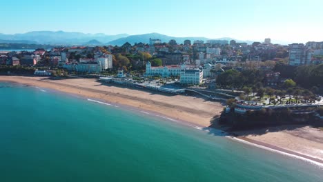 Europäischer-Strand-In-Der-Nähe-Der-Stadt,-Mit-Blauem-Wasser-Und-Bergen-Im-Hintergrund