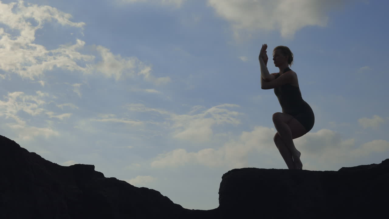 Silhouette of woman in Eagle pose practicing yoga