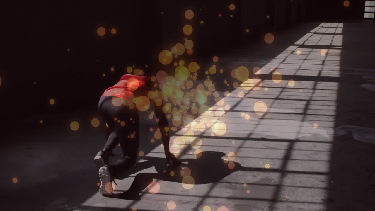 출발 위치에 있는 아프리카계 미국인 여성의 뒷면에 오렌지색 빛의 반점이 달릴 준비가 되어 있습니다.