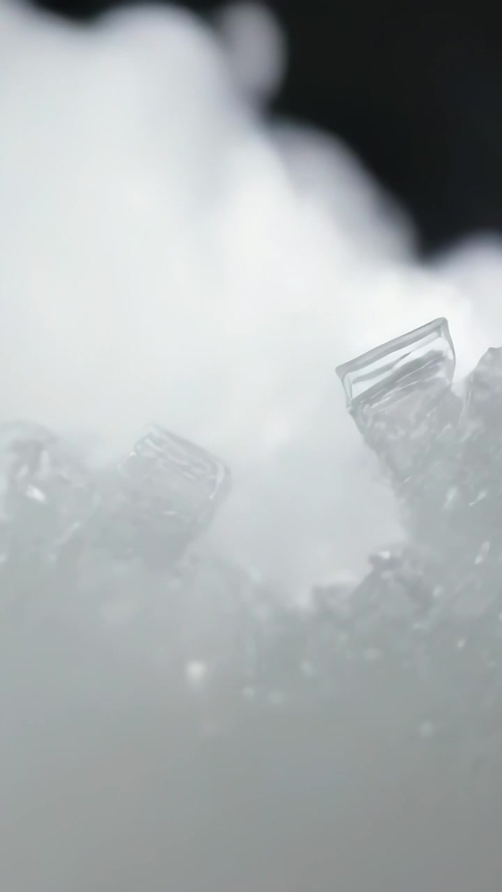 Video verticale: Spostamento della messa a fuoco della telecamera per rivelare un gruppo di cristalli su brina con vapore su sfondo nero.