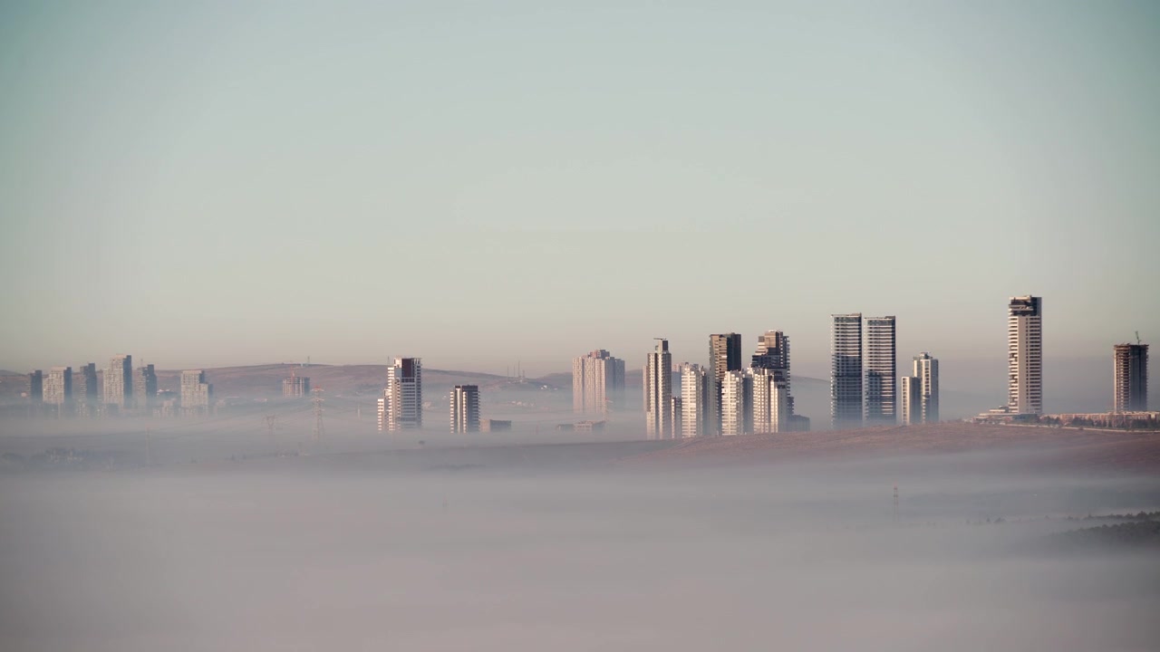 Skyline di città moderna che emerge sopra una fitta nebbia mattutina