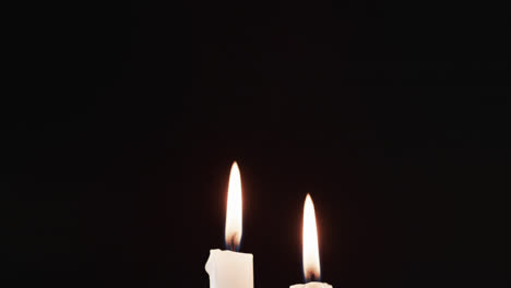 Video-of-two-white-candles-with-white-flame-and-copy-space-on-black-background