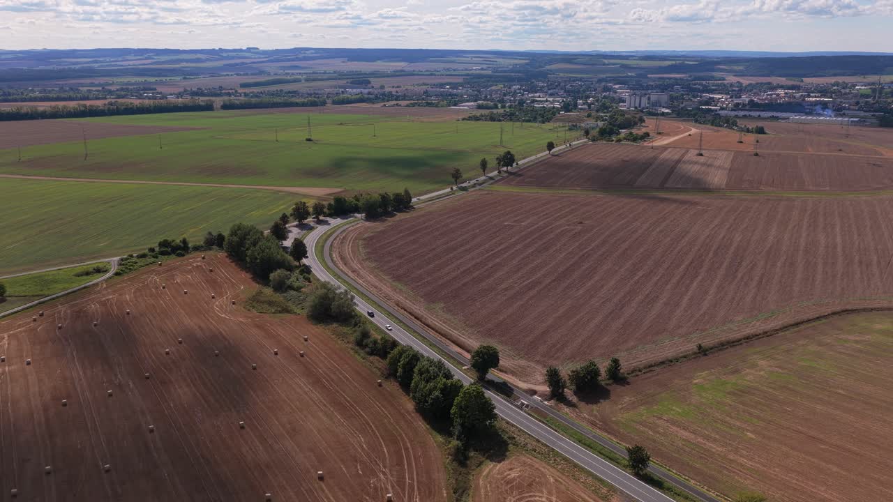Road leading to the city through rural landscape of fields. Fertile land from aerial view. Czech Republic