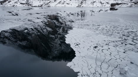 POV-footage-of-a-winter-boat-journey-through-Norway's-Geirangerfjord,-capturing-stunning-views-of-ice-in-the-water-from-the-surrounding-snowy-mountains