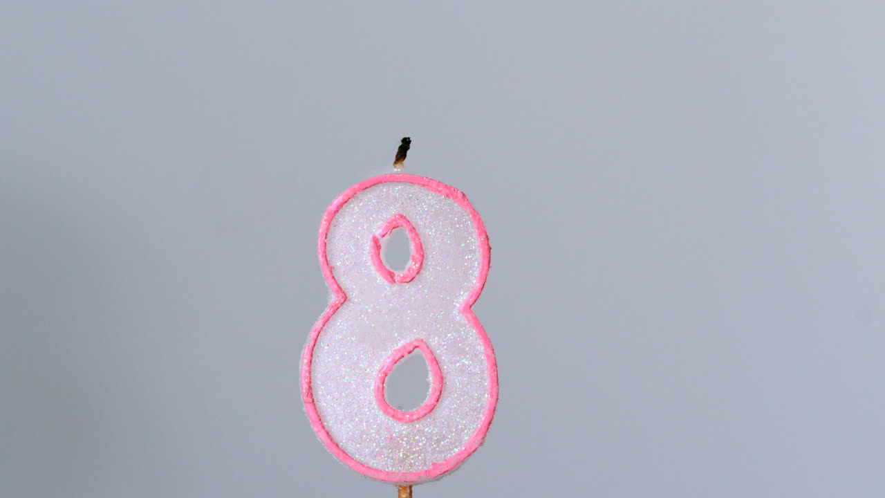 ocho velas de cumpleaños parpadeando y apagándose sobre un fondo gris