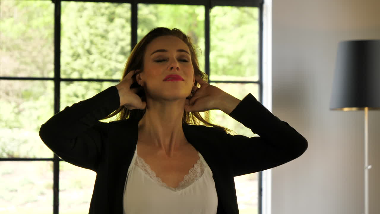 mujer madura atractiva sensual pasando por su cabello y sonriendo en la cámara, cámara lenta