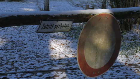 pan shot coming to a stop on a sign saying "zutritt verboten" with snow on the ground in autumn in germany