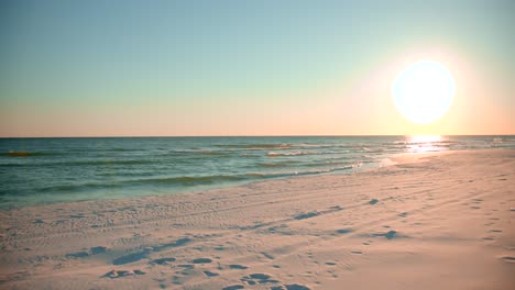 shots of the ocean on a warm, sunny evening with footprints in the sand facing the sun directly-2