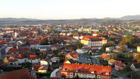 Aerial-Panorama-view-of-small-medieval-european-town-Slovenska-Bistrica,-Slovenia-with-church-and-castle-in-sunrise