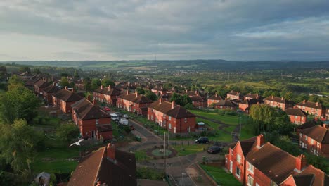 Vida-Urbana-En-El-Reino-Unido:-Un-Vídeo-Aéreo-Con-Un-Dron-Captura-La-Finca-Municipal-De-Ladrillo-Rojo-De-Yorkshire-Bajo-El-Cálido-Sol-De-La-Mañana,-Mostrando-Casas-Y-Personas-En-Las-Calles.