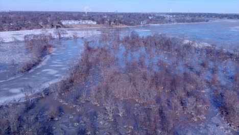 Drone-shot-flying-over-flooded-Audubon-Society-island-of-woods-and-rocks-in-the-middle-of-winter